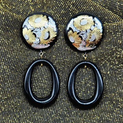Pair of earrings with floral designs on a textured fabric background