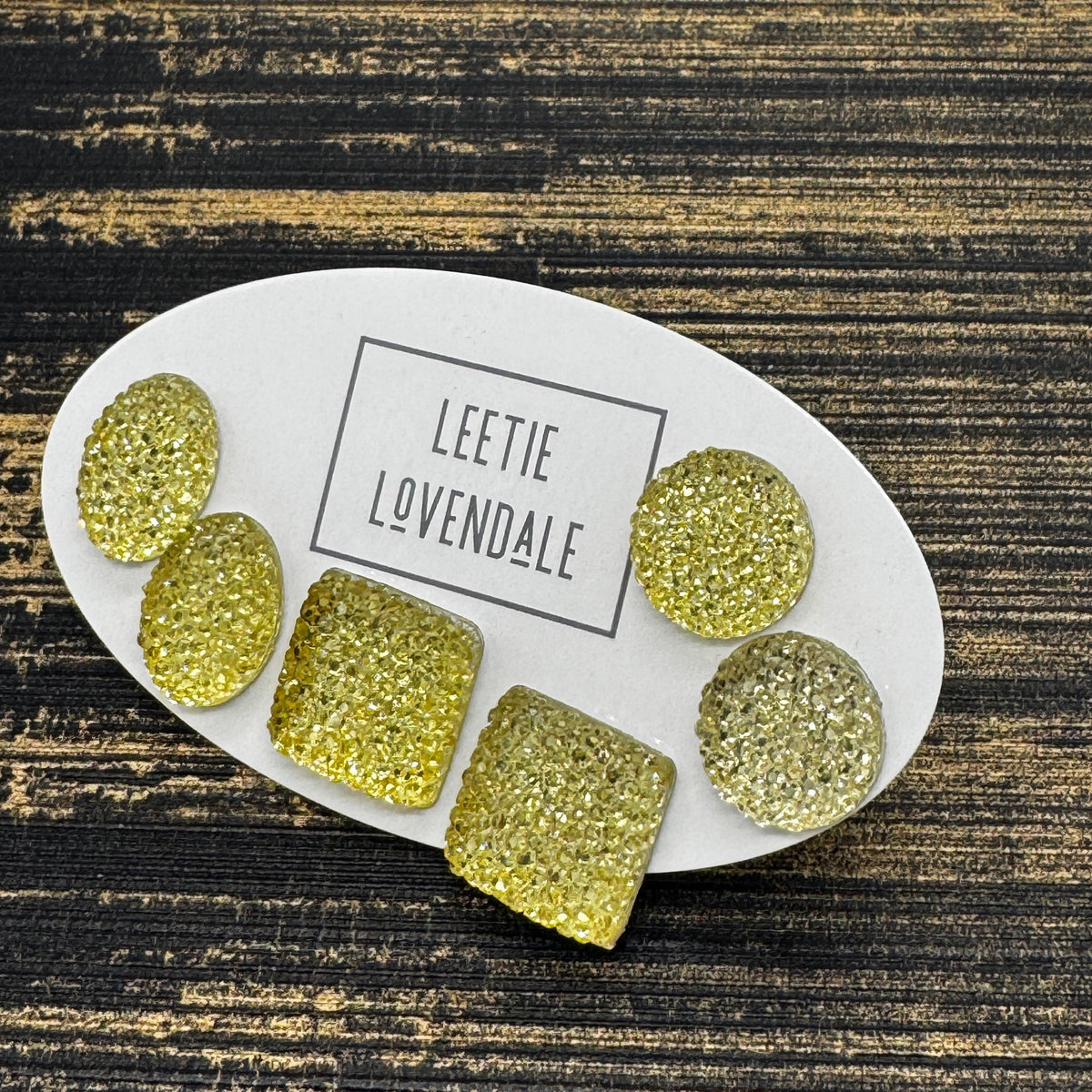 Yellow textured stud earrings on a white card with Leetie Lovendale branding on a white background.